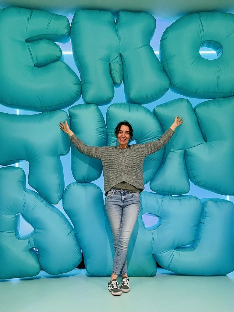Anna Krieger vor einer Wand aus türkisfarbenen Buchstaben-Ballons
