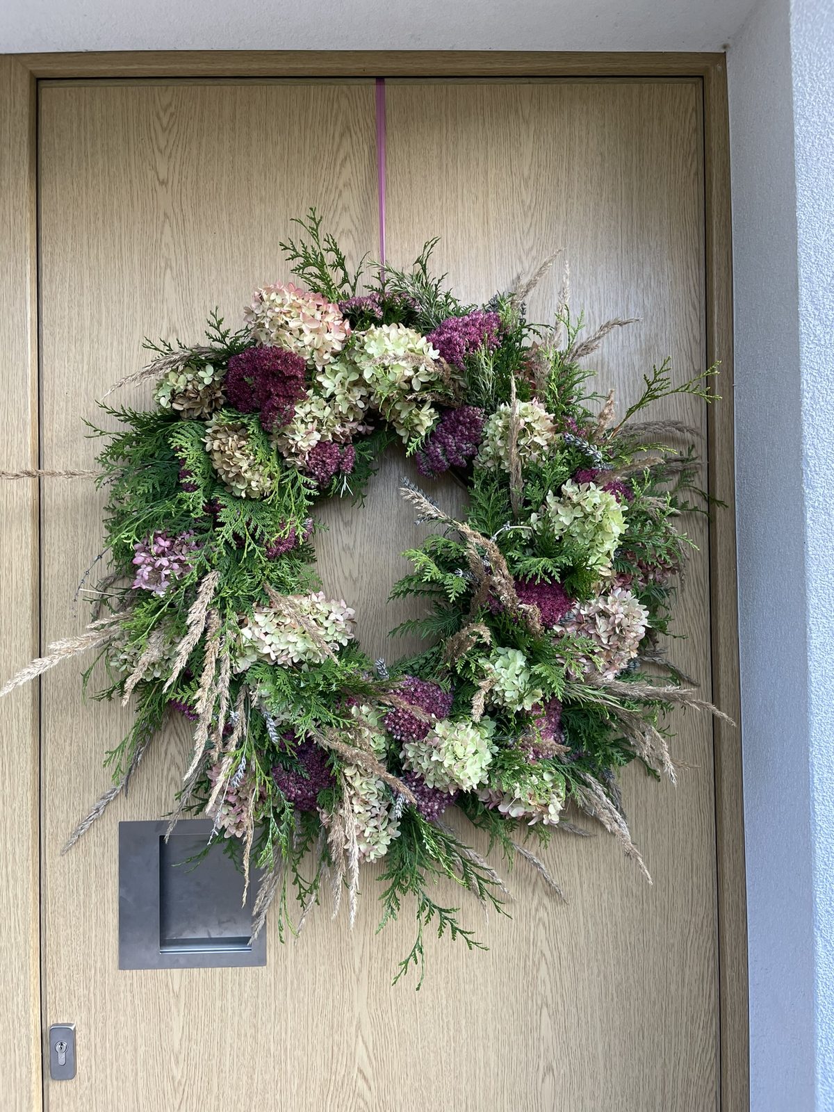 Herbstkranz mit Hortensien und Gräsern an einer Haustür